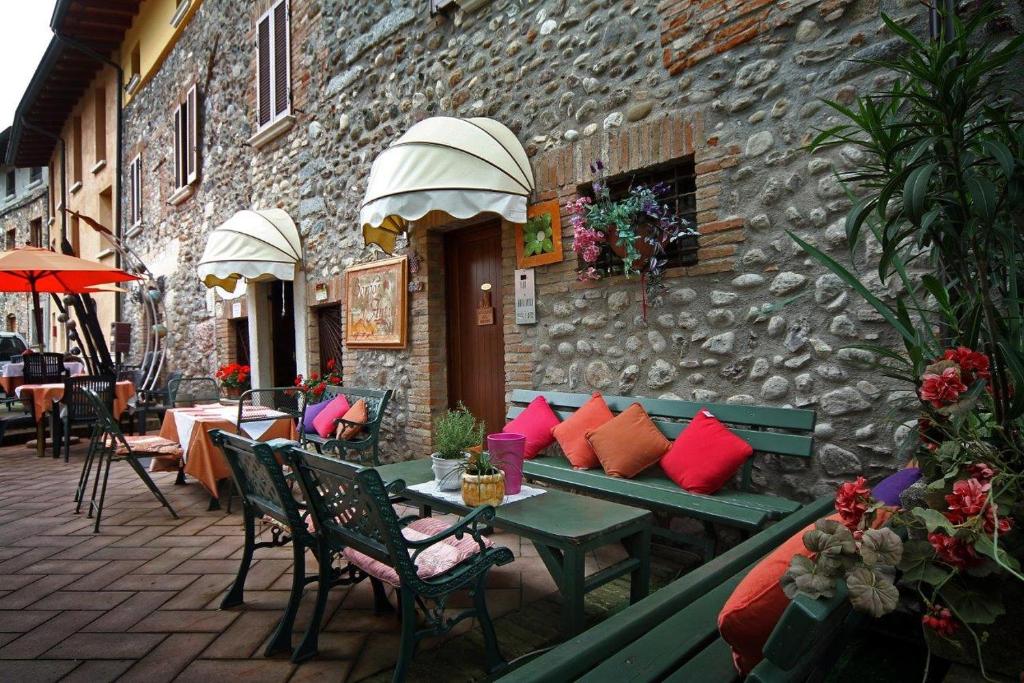 bedizzoleAL BORGO ANTICO Ristorante con camere的一座带桌椅的庭院和一座石头建筑