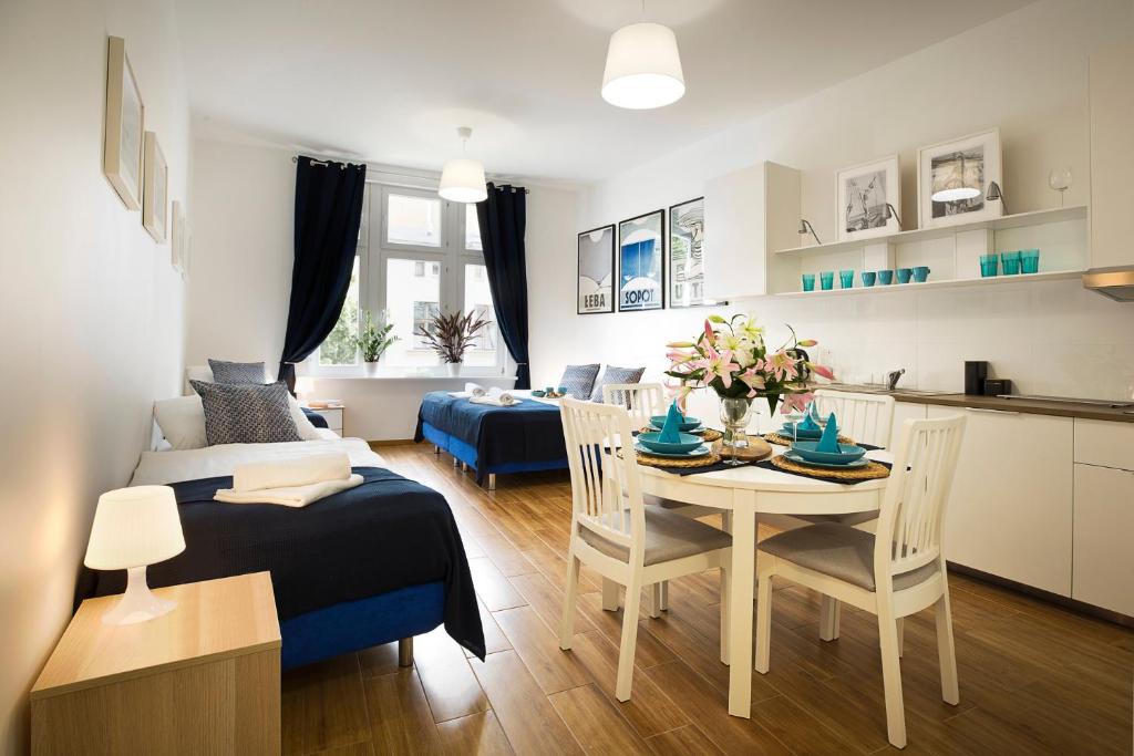 索波特Monte Cassino Apartments的客厅以及带桌椅的厨房。