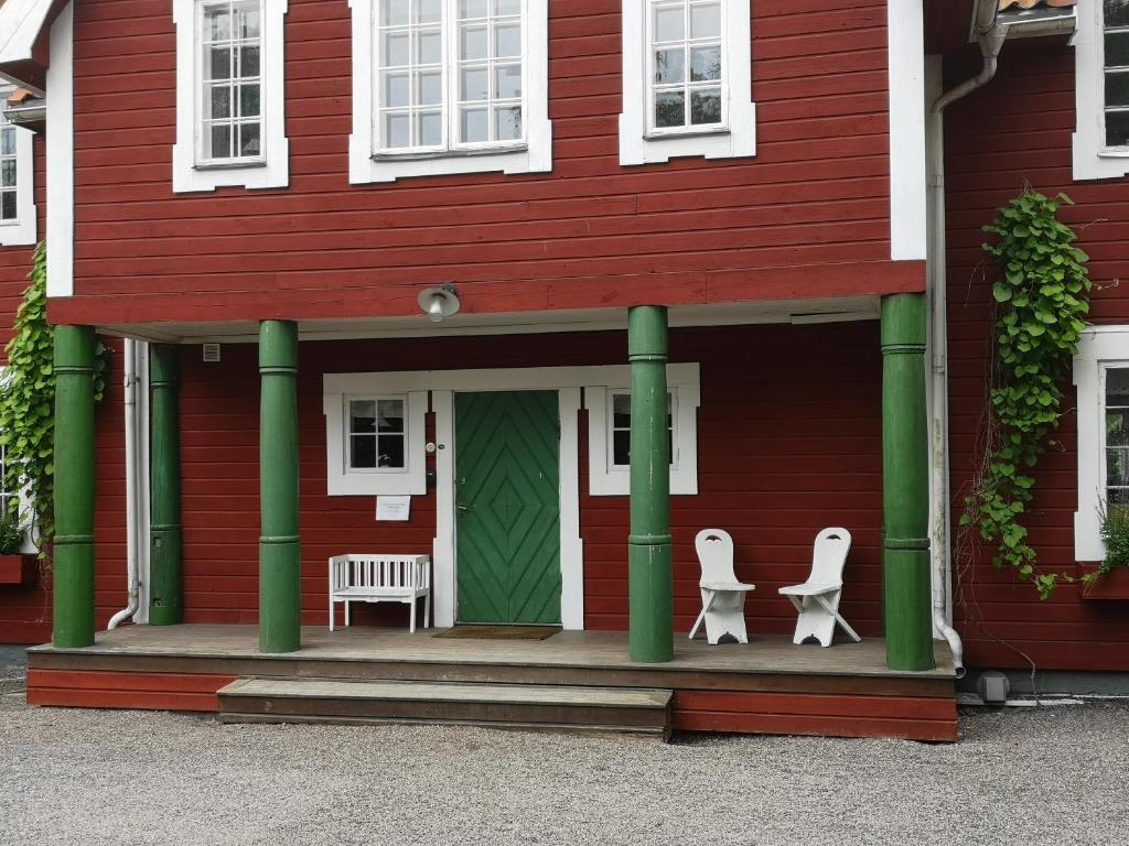 纳卡Stockholm B&B Cottage的门廊上设有两把白色椅子的红色房子