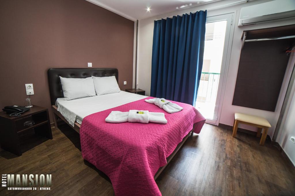 雅典曼森酒店的一间卧室配有一张床,上面有两条毛巾