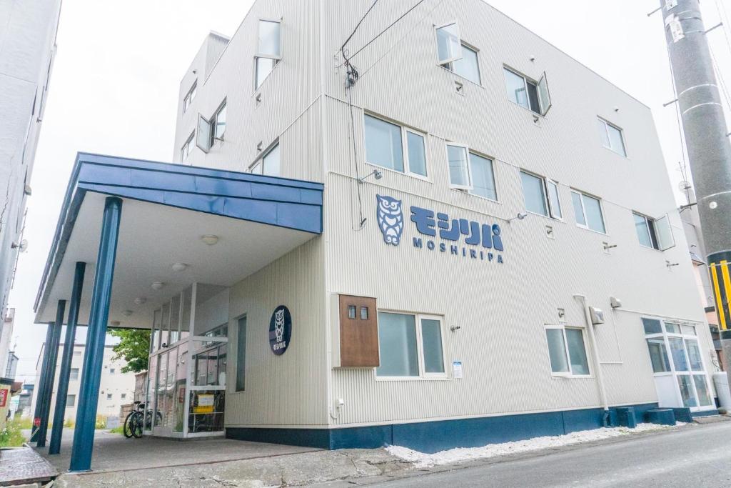 稚内Guest House Moshiripa的一条白色的建筑,在街上有一扇蓝色的门