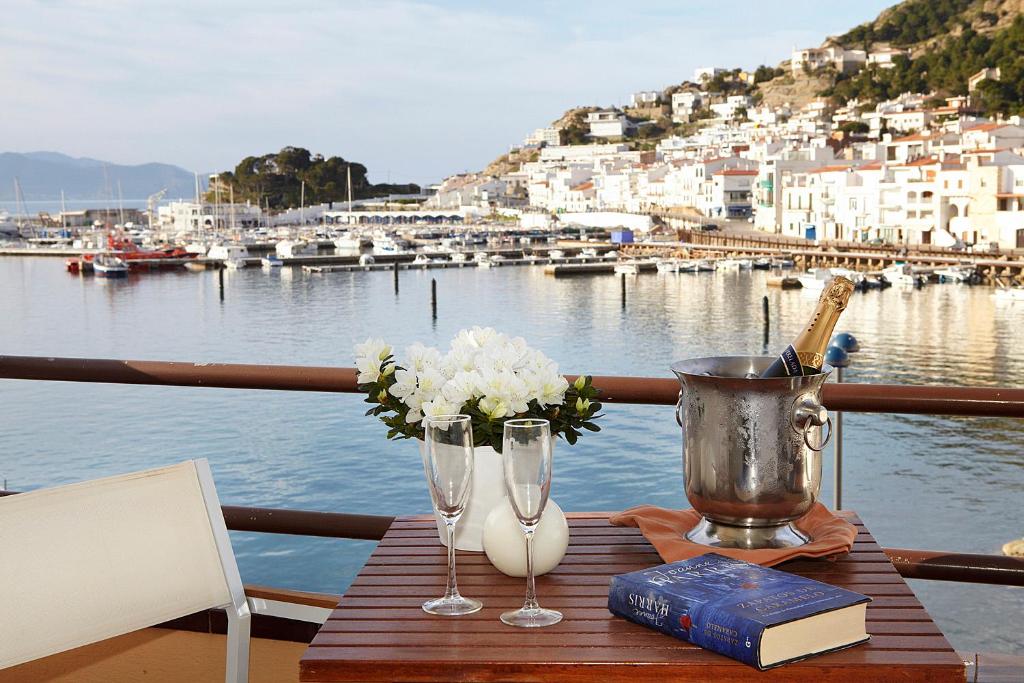 德拉塞尔瓦港Hotel Spa Cap de Creus的一张桌子,上面放着两杯酒,船上还有一本书