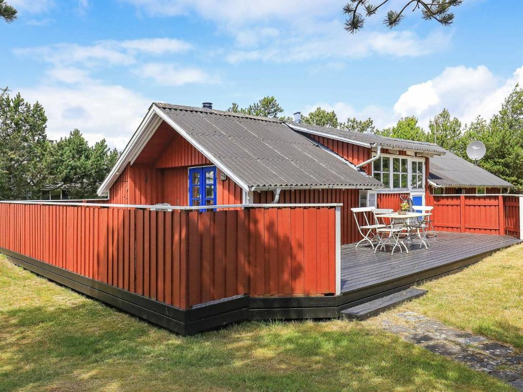 齐斯泰兹4 person holiday home in Thisted的红色的房子,设有甲板和桌子