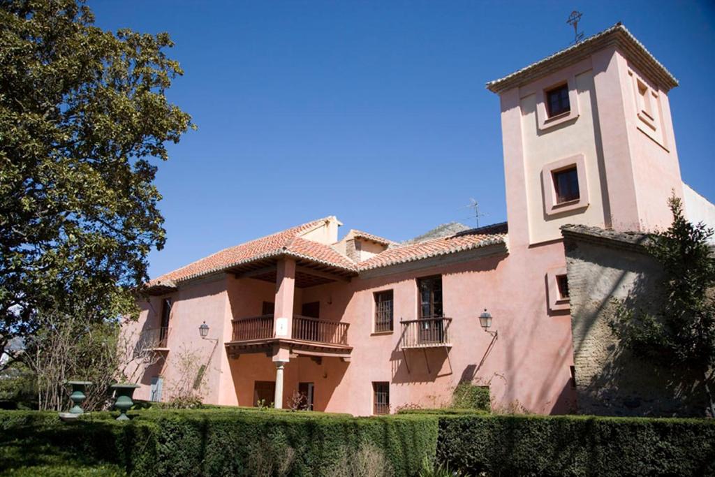 NigüelasCasa Mosaico Granada en el V de Lecrin的一座大型粉红色建筑,带有塔楼和栅栏