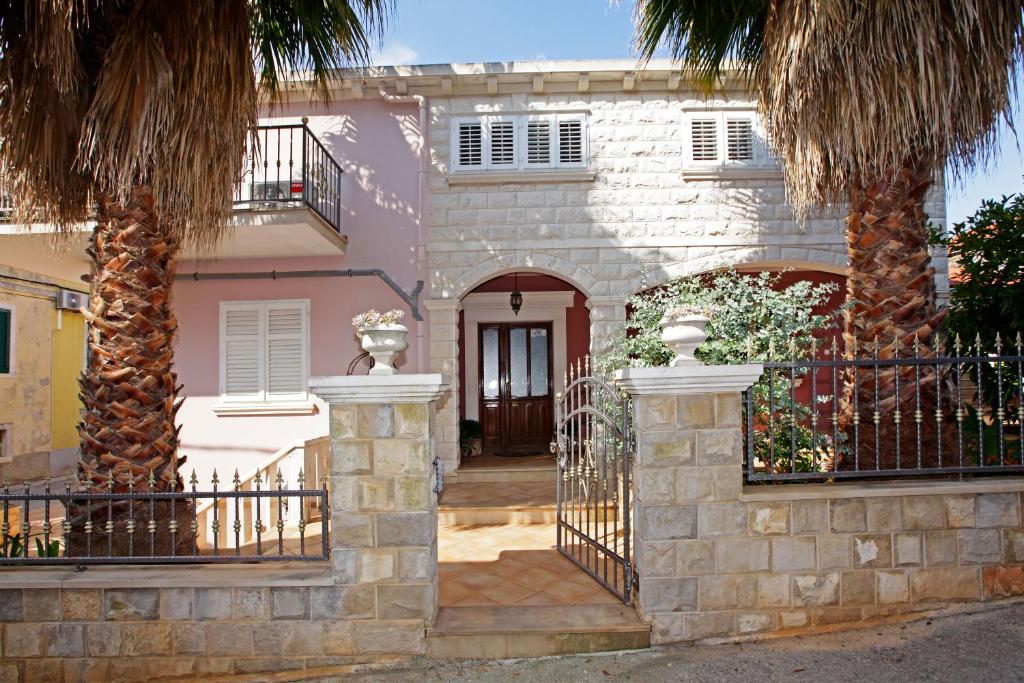 尼亚卢卡Apartment Ambroz的一座带大门和两棵棕榈树的房子