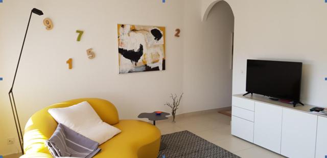 洛索内GRETA 29的客厅配有黄色椅子和平面电视