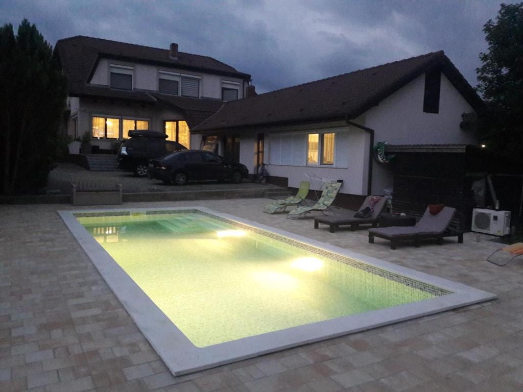 赫维兹Respect Apartament的夜间在房子前面的游泳池