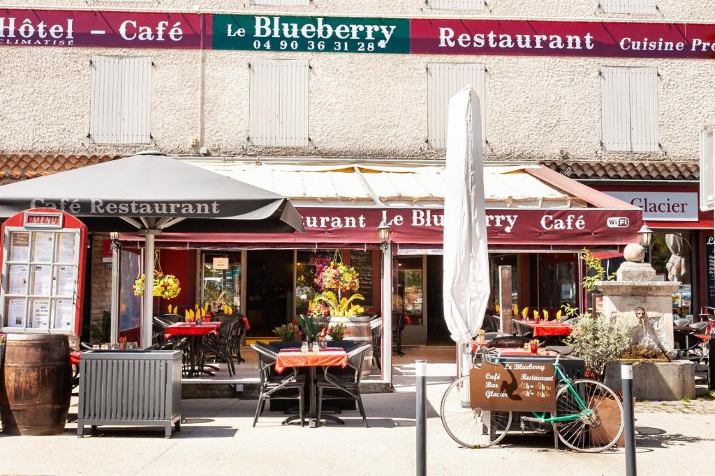 马洛塞讷Hôtel-Restaurant Le Blueberry的一间带桌椅和遮阳伞的餐厅以及自行车
