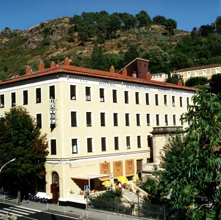 巴尼奥斯德蒙特迈奥尔巴尔内阿里奥坎大酒店的一座白色的大建筑,背景是一座山