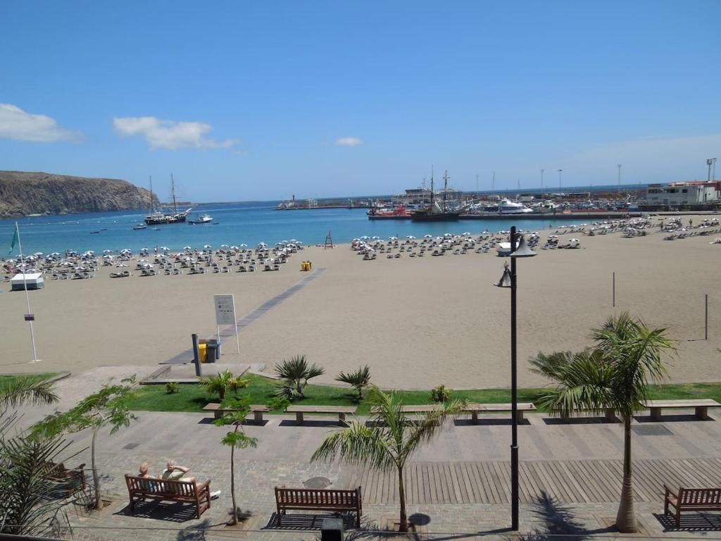 阿罗纳Casa Azul only 200 meters to the beach, free wifi, balcony的一个带长椅和遮阳伞的海滩和一群人的海滩