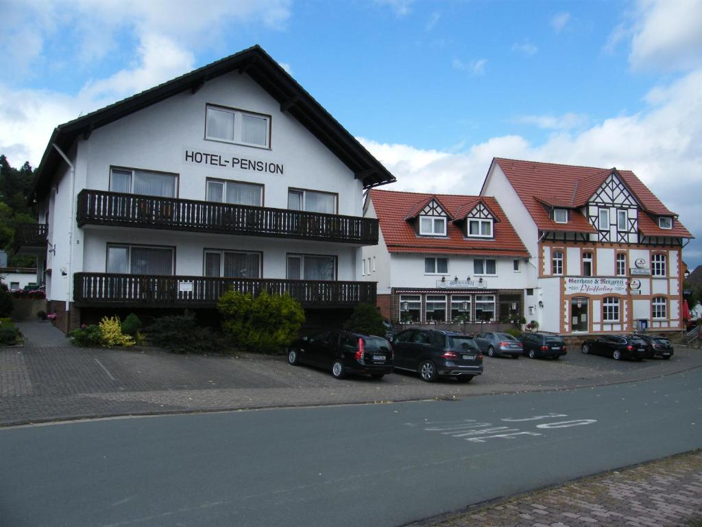 沃尔夫根Gasthaus Hotel Pfeifferling的一座白色的建筑,前面有汽车停放