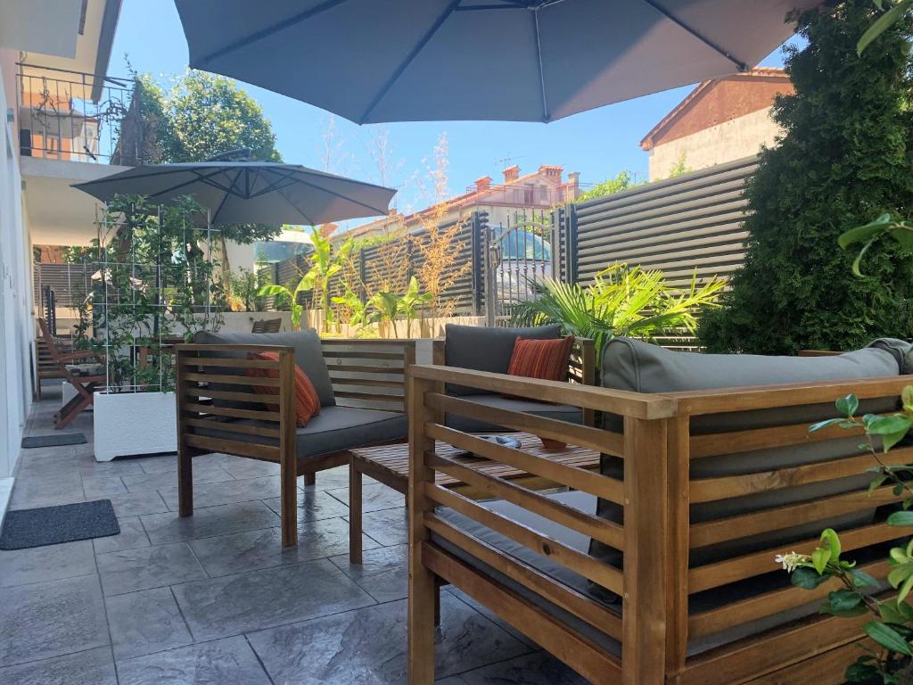 伊佐拉Apartments Artemus Karliva的庭院设有2张长椅和遮阳伞。