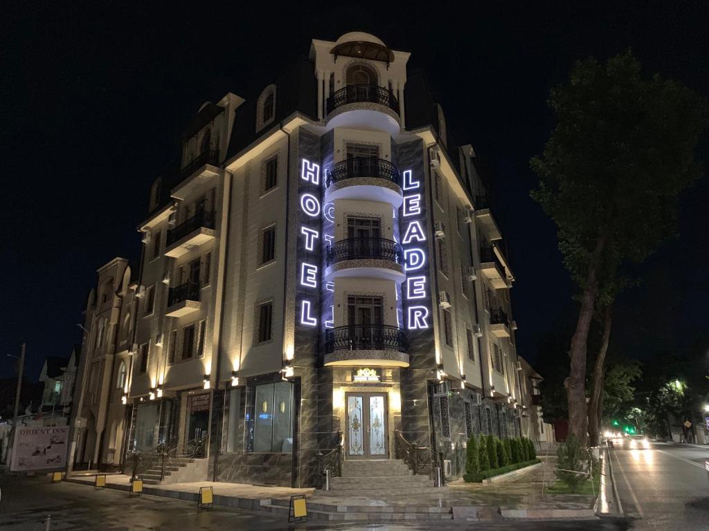 塔什干Leader Hotel的一座建筑物,晚上在建筑物的一侧有标志