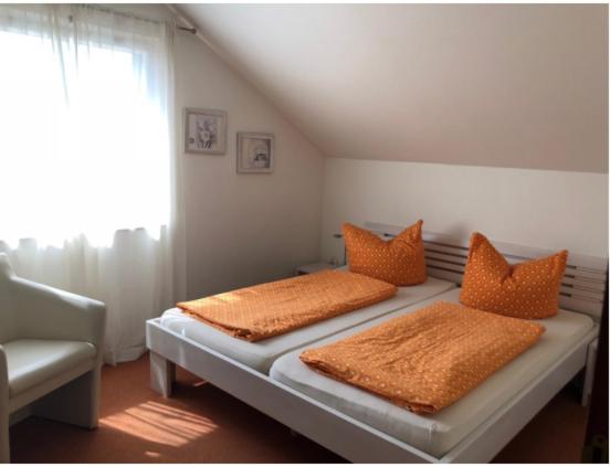 蒂宾根Gasthof ´s Gräbele的一间卧室配有两张带橙色枕头的床