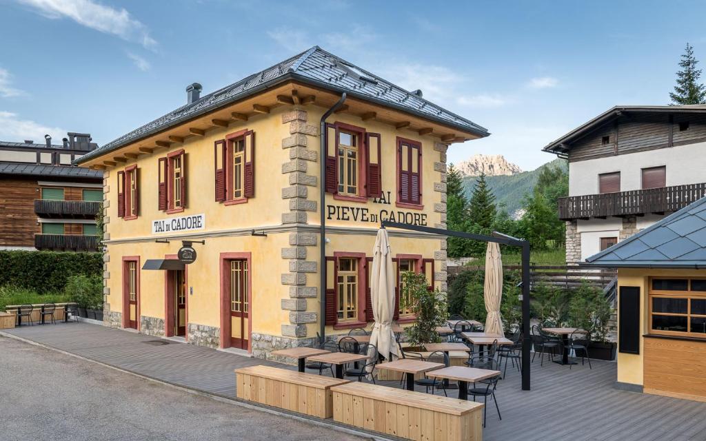 皮耶韦迪卡多雷Alla Stazion Locanda nelle Dolomiti的前面有桌子和伞的建筑