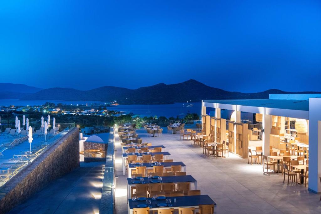 伊罗达Elounda Breeze Resort的夜间带桌椅的酒店庭院