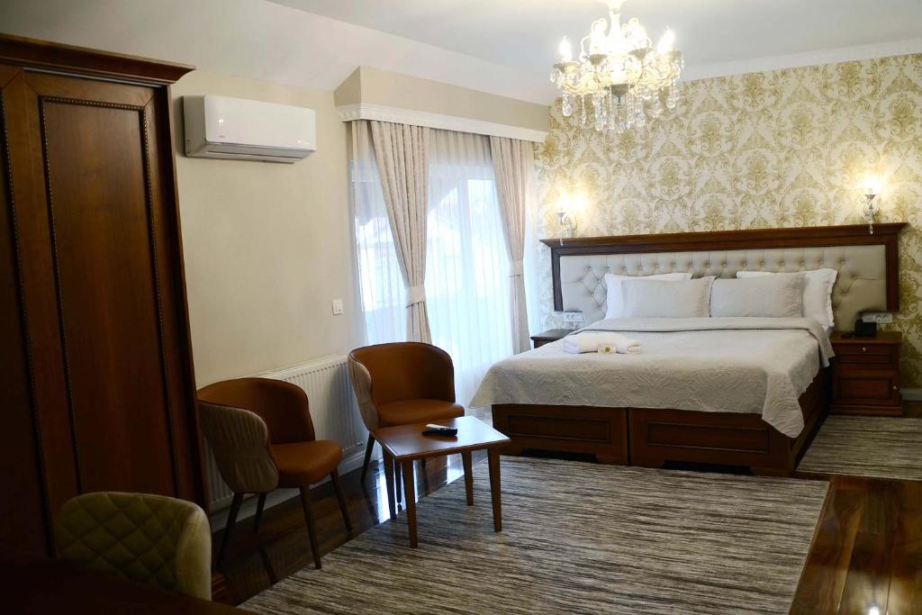普里什蒂纳贝戈利酒店的一间卧室配有一张床、两把椅子和一个吊灯
