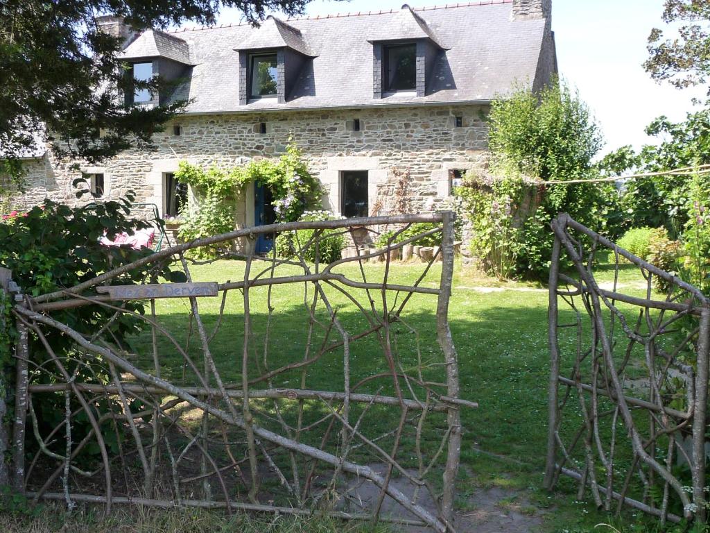 Pleumeur-GautierBretagne Chambre d'hôtes suite 53m2 et Caravane vintage avec cuisine et salle de bains privées Brittany B&B 53m2 suite and Vintage caravan glamping with private kitchen and bathroom的一座古老的石头房子,前面有门