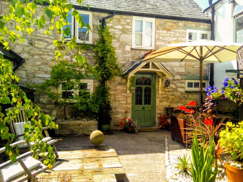 里辛Castle Street Cottage的一座石头房子,设有绿门和遮阳伞