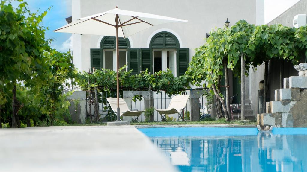 莫尔曼诺Il Casino di Donna Maria的一个带遮阳伞和椅子的游泳池以及一座房子