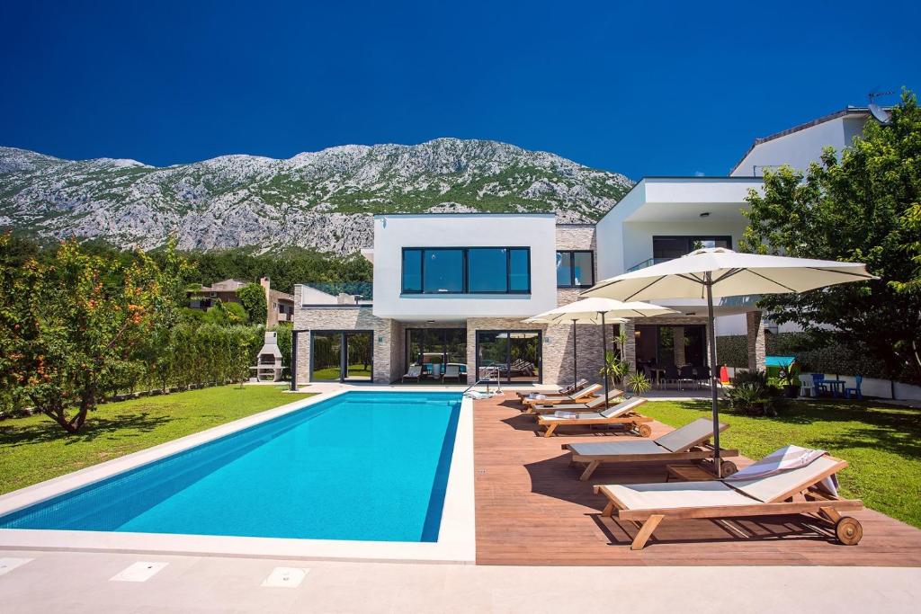 加塔Villa Agava with heated pool, Jacuzzi, sauna, gym, 4 en-suite bedrooms的别墅 - 带带椅子和遮阳伞的游泳池