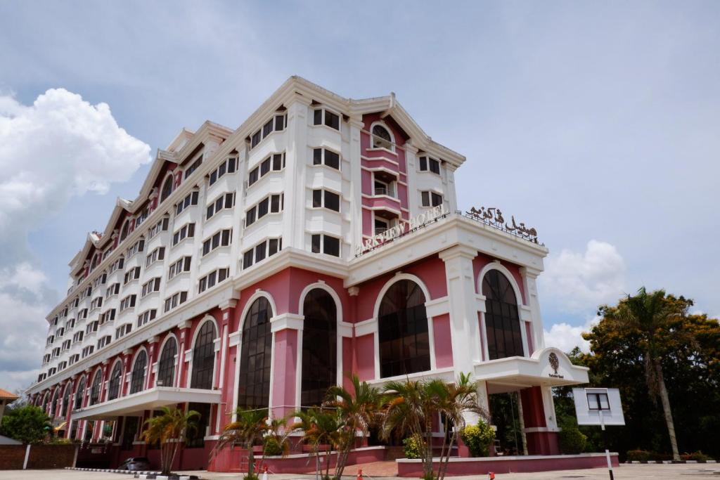 甘榜杰鲁登园景酒店的一座粉红色和白色的建筑,前面有棕榈树