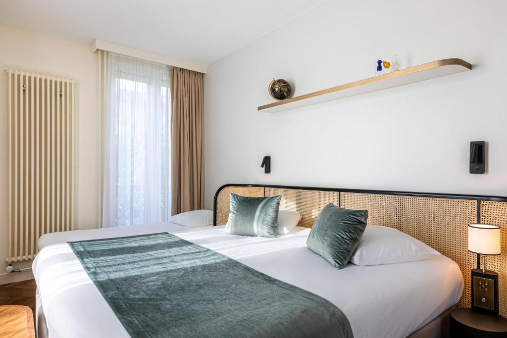 巴黎Hotel Le Friedland的卧室配有带绿色枕头的大型白色床