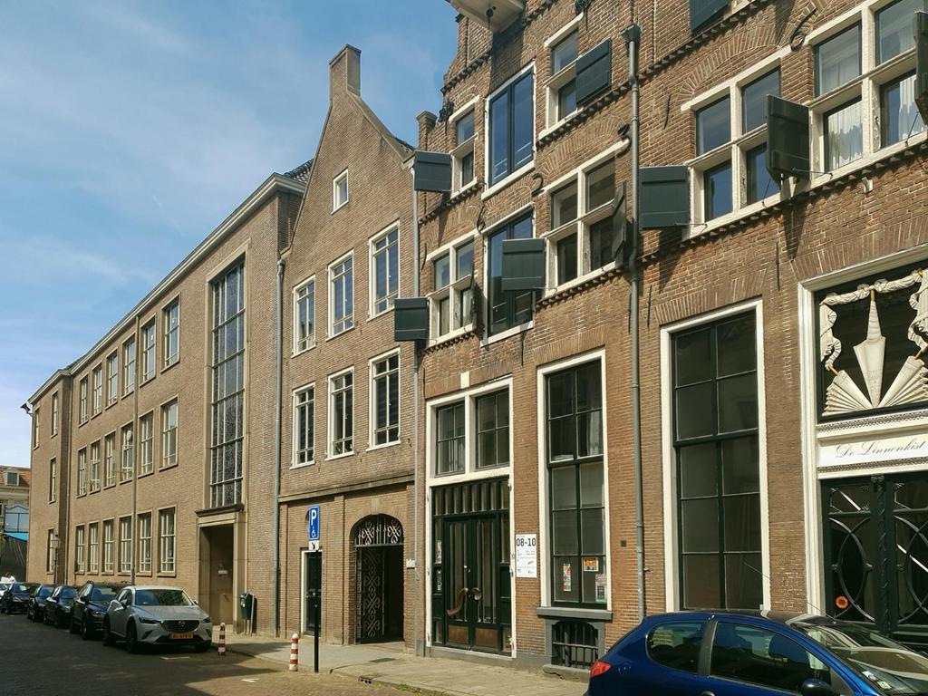 迪温特Citystays Deventer的一座大型砖砌建筑,前面有汽车停放