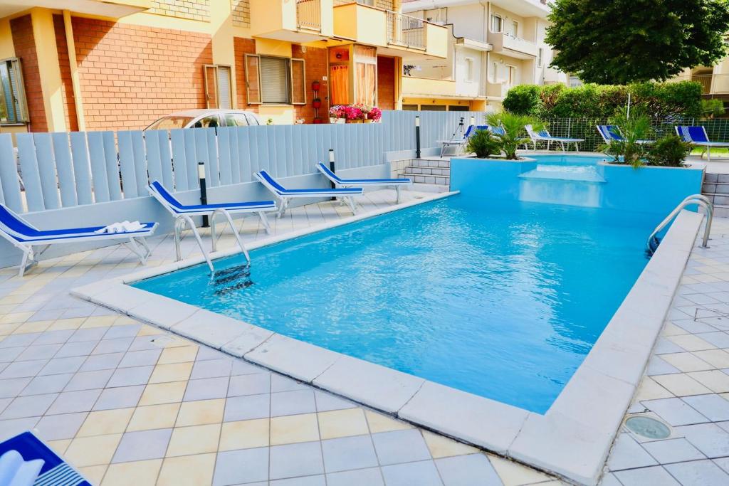 里米尼Hotel A Casa Nostra的一个带蓝色椅子和围栏的游泳池