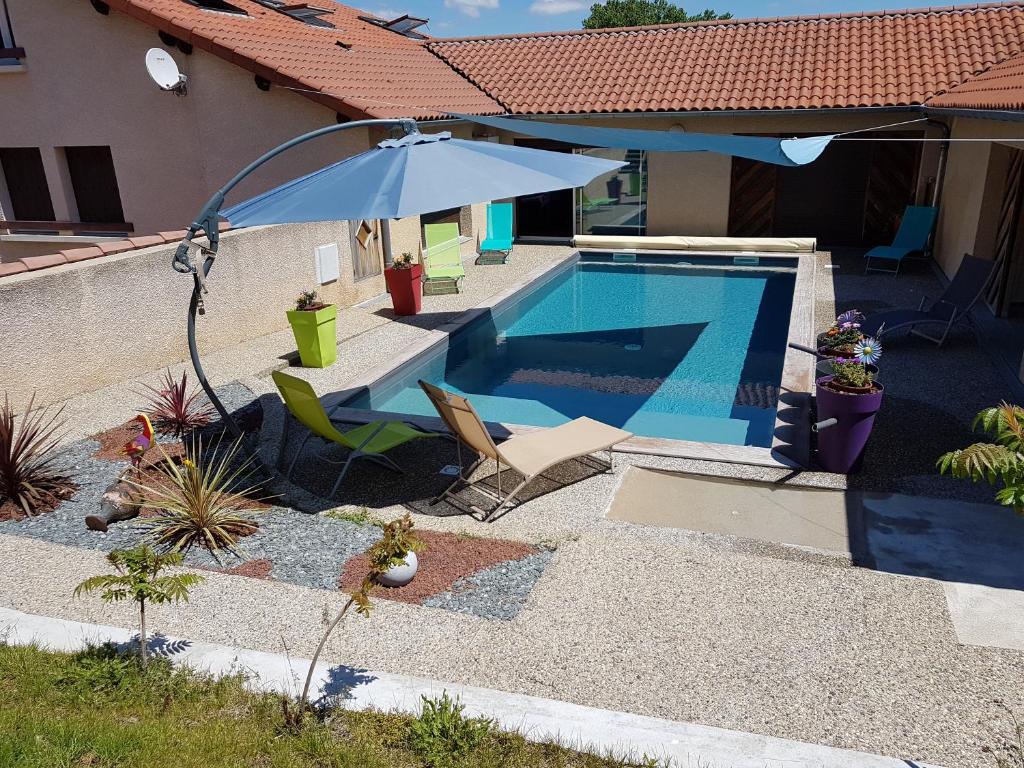 Reilhac阿里尔河酒店的一座房子旁的游泳池,配有遮阳伞和椅子