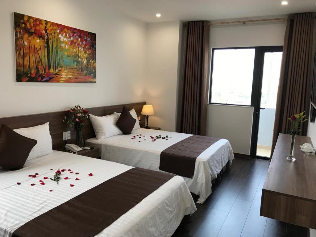 洞海Windy Hotel Quang Binh的酒店客房设有两张床,墙上挂有绘画作品