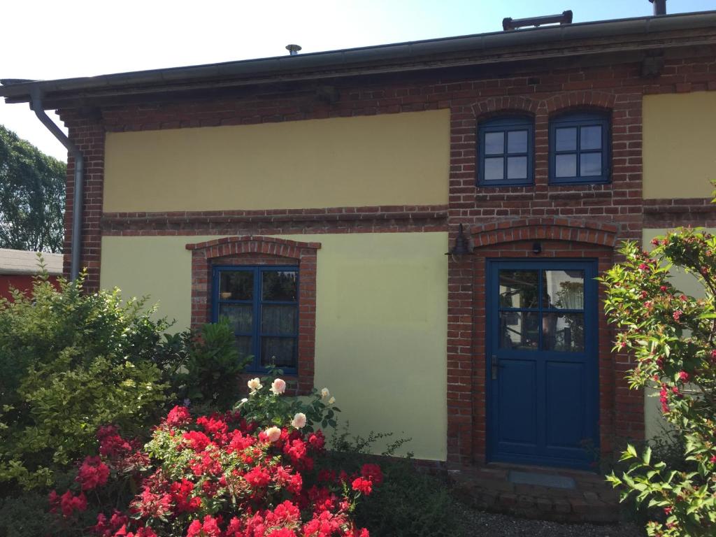 奥斯特巴德里克Romantische Ferienhaus an der Ostsee mit großem Garten的一座砖房,有蓝色的门和鲜花