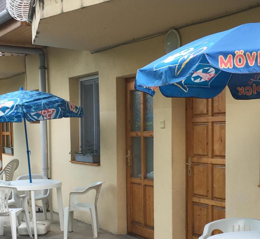 鲍洛通塞迈什Fasor vendégház的两把蓝色遮阳伞,坐在桌子和椅子旁边