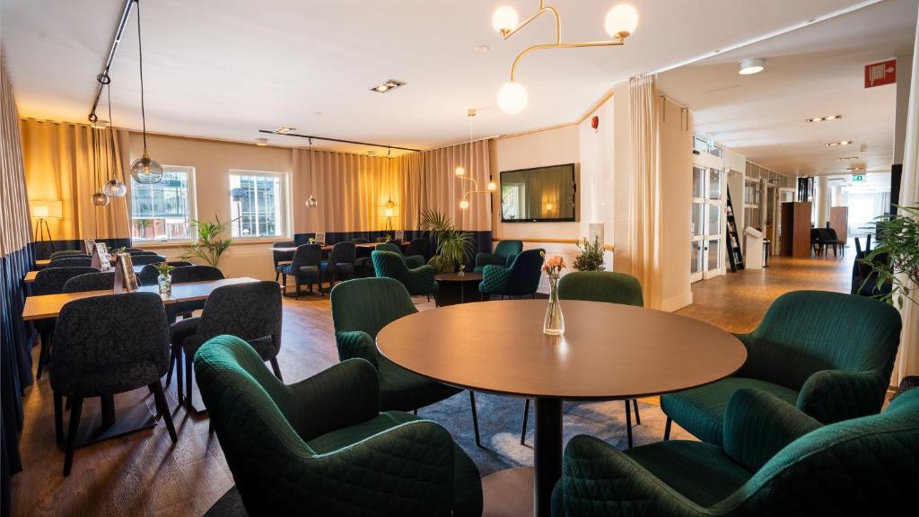 瓦尔贝里福来加藤克拉丽奥集团酒店的一间设有桌子和绿色椅子的等候室