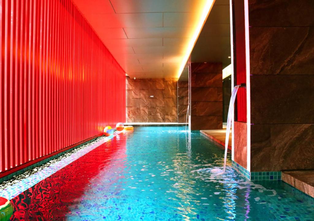 马尼拉Red Hotel Cubao, Quezon City的拥有红色墙壁和蓝色海水的游泳池