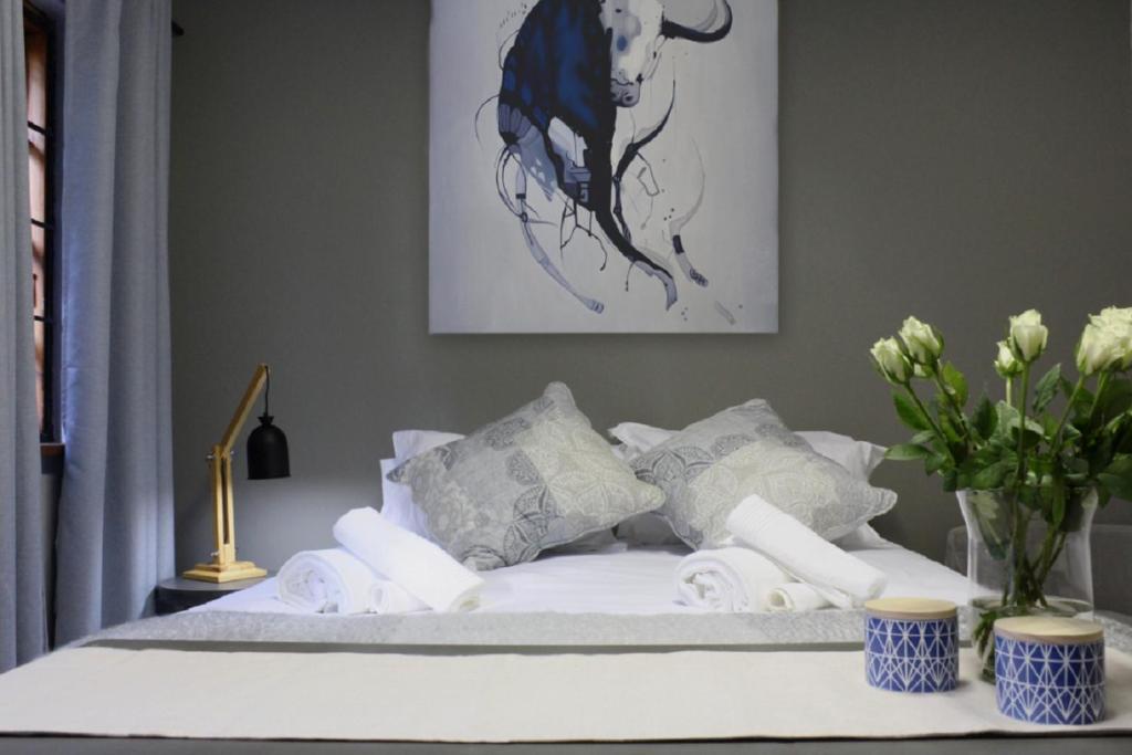 比勒陀利亚Guesthouse @ 31 Murray的一张带白色床单和枕头的床和花瓶