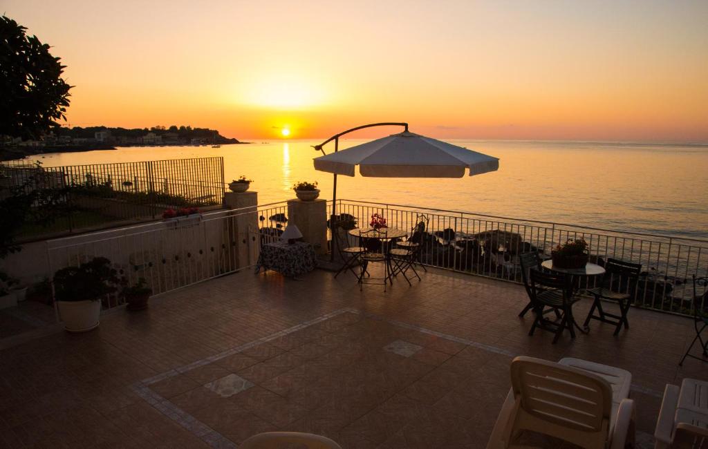 阿茨特雷扎Appartamento in Villa Agnese的阳台上的日落美景,配有桌子和遮阳伞