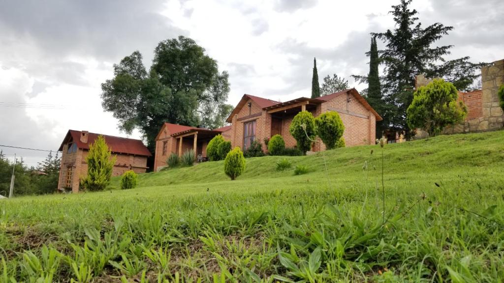 瓦斯卡坎波Cabañas villa de San Miguel的一座带教堂的草山上的房子
