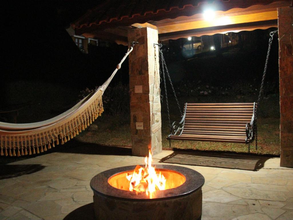 蒙特韦尔迪Pousada Winterhaus的一个带吊床的火坑和夜间的长凳