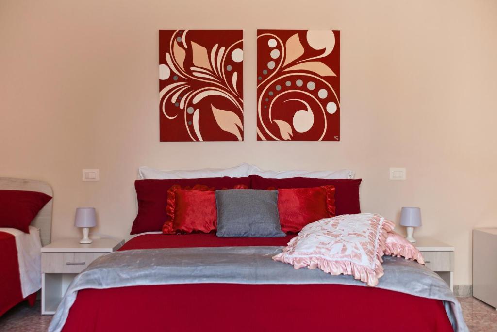 SanaricaB&B Mamma Carolina的卧室配有红色的床,墙上挂有两幅画作