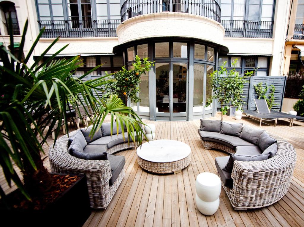 巴塞罗那兰布拉普拉提克酒店的庭院配有柳条家具和桌椅