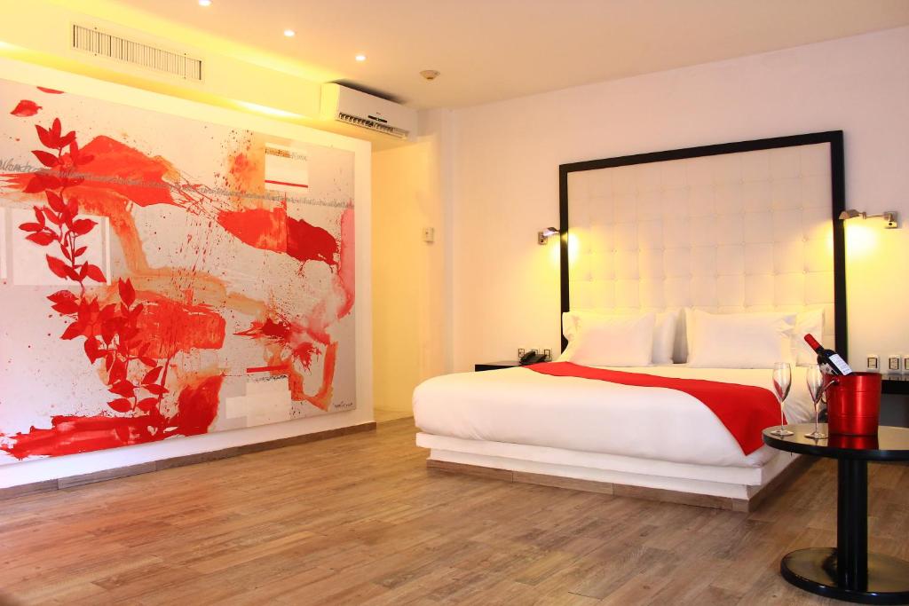 普拉亚卡门In Fashion Hotel & Spa的卧室配有一张床,墙上挂有绘画作品