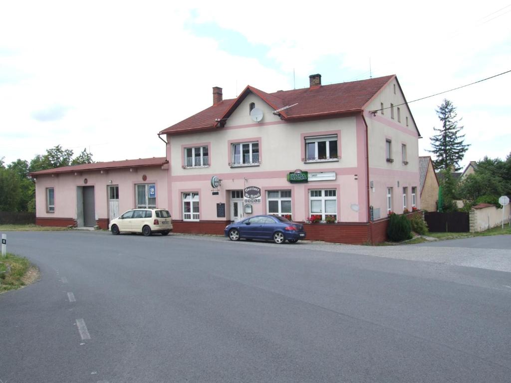 亚沃尔尼克Hostinec Na Návsi的一座粉红色的房子,前面停有两辆车