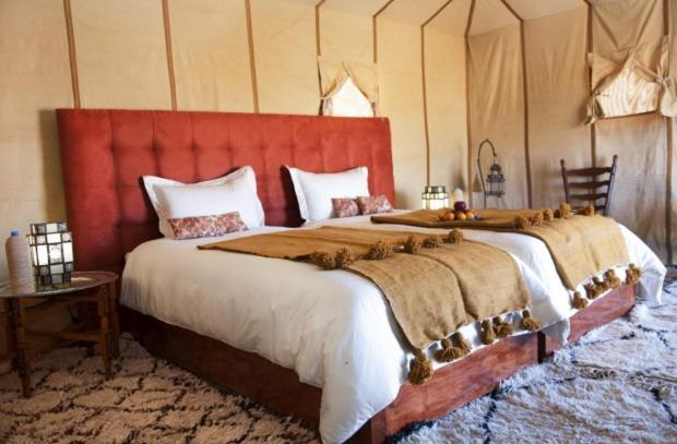 Foum ZguidMaroc Sahara Luxury Camp & Tours的一间卧室配有一张大床和红色床头板