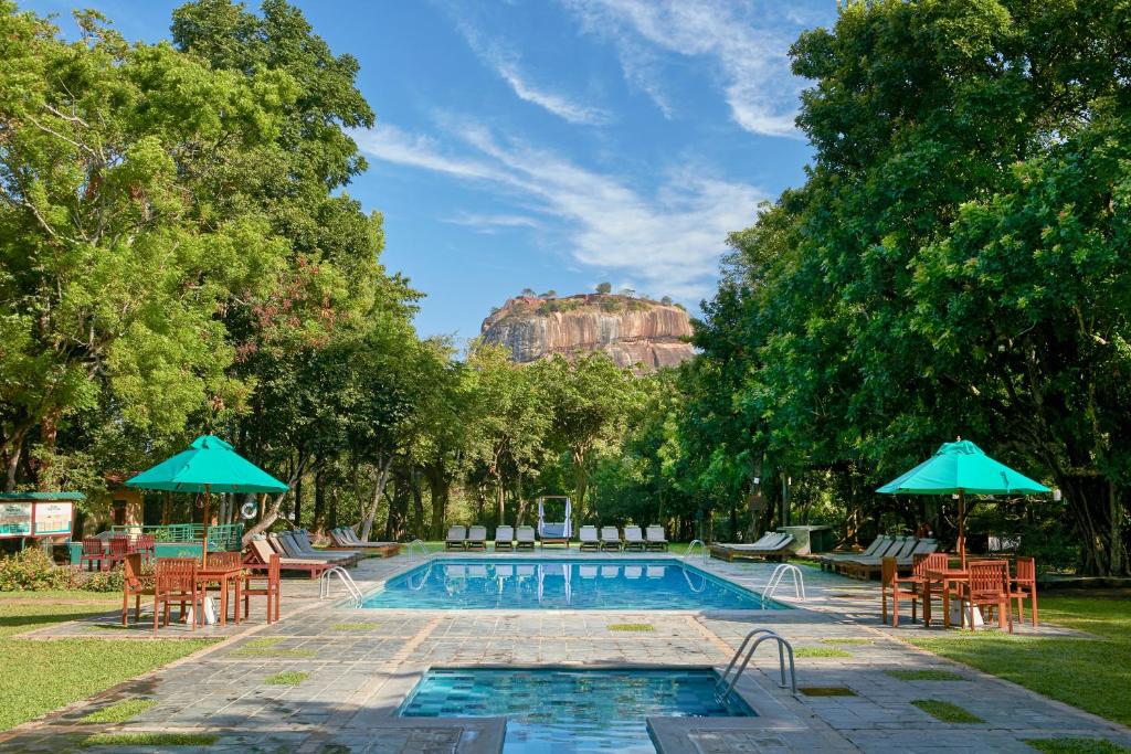 锡吉里亚锡吉里亚酒店的游泳池旁设有椅子和遮阳伞