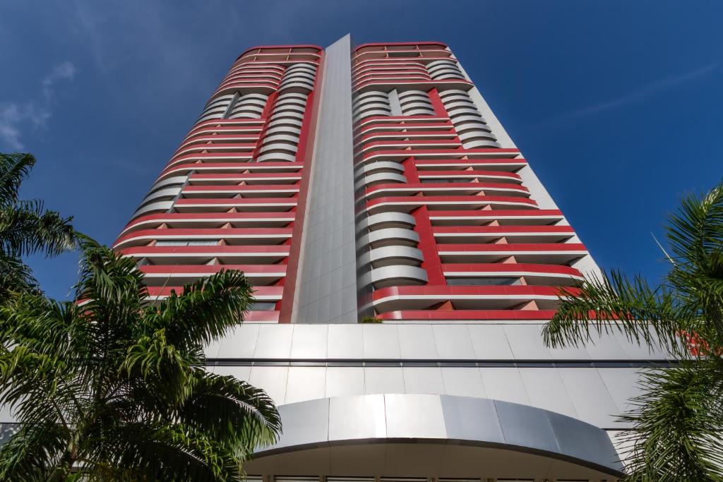 萨尔瓦多Boulevard Residencial的一座高大的红色建筑,前面有棕榈树