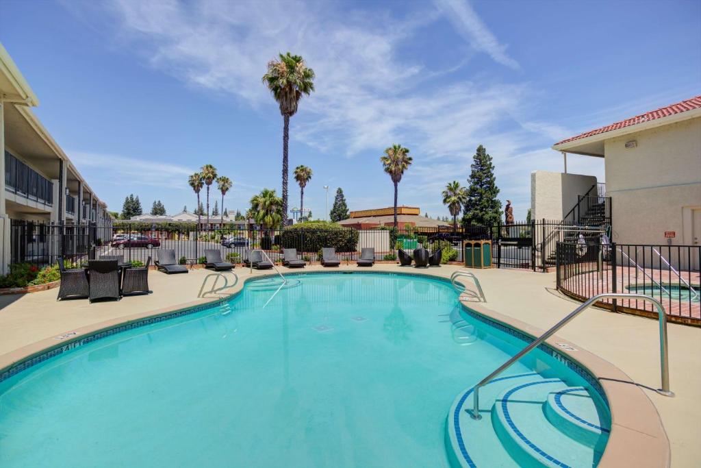 萨克拉门托Best Western Sandman Hotel的一个带椅子和棕榈树的大型游泳池