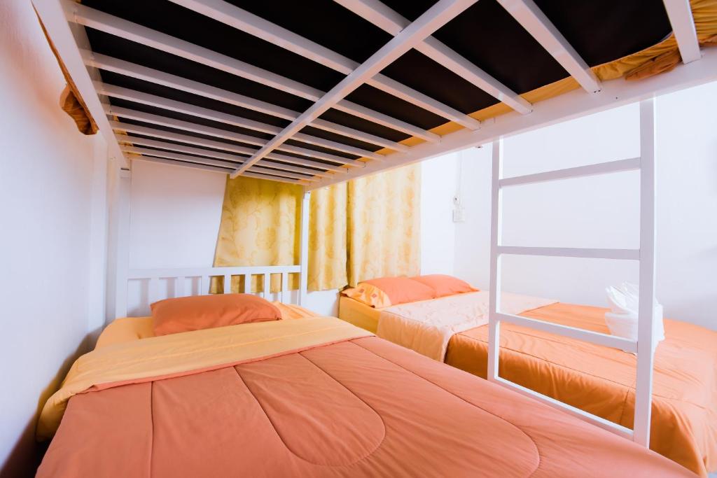 素叻纳德珀博旅馆的配有橙色床单的客房内的两张床