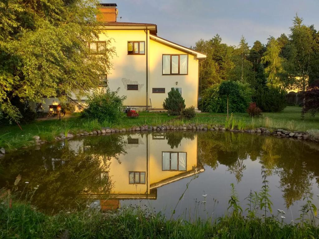 DreiliņiGuest House Pechersky & Sons的前面有池塘的房子