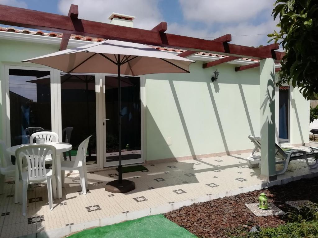 卡尔达斯达·赖尼亚Villa Gonçalo的庭院配有遮阳伞和桌椅。